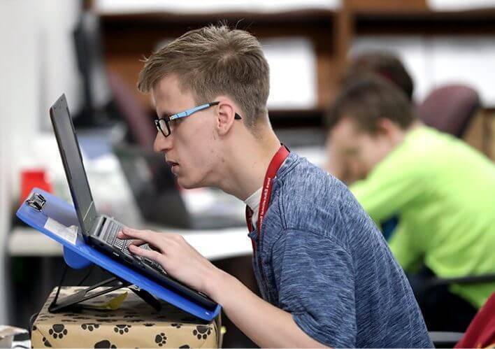A student reading from the screen of a laptop computer.